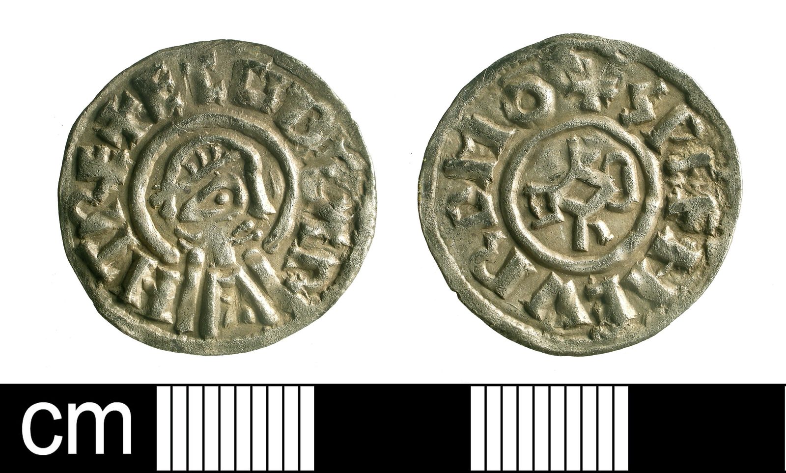 Both faces of a silver penny beside a scale bar, a portrait head on one side.